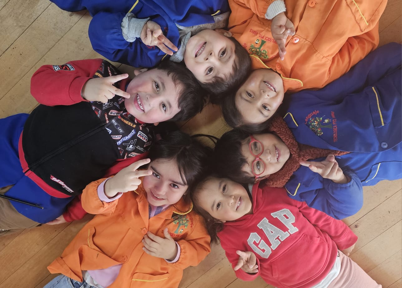 Niños acostados en círculo mirando hacia arriba